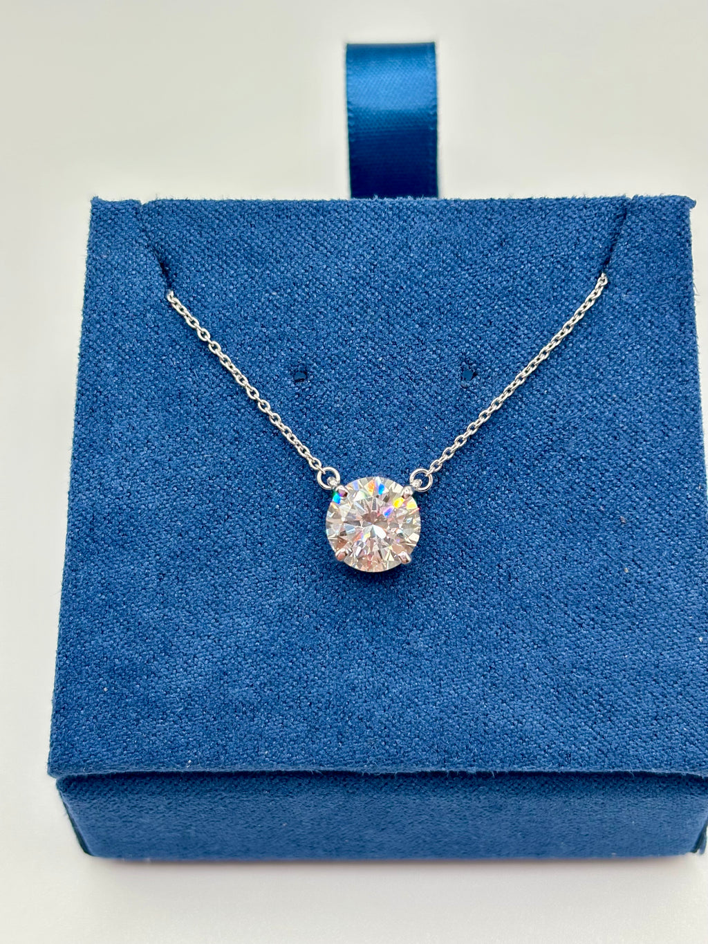 2 carat lab diamond solitaire station necklace in 14K white gold on blue velvet box, top view