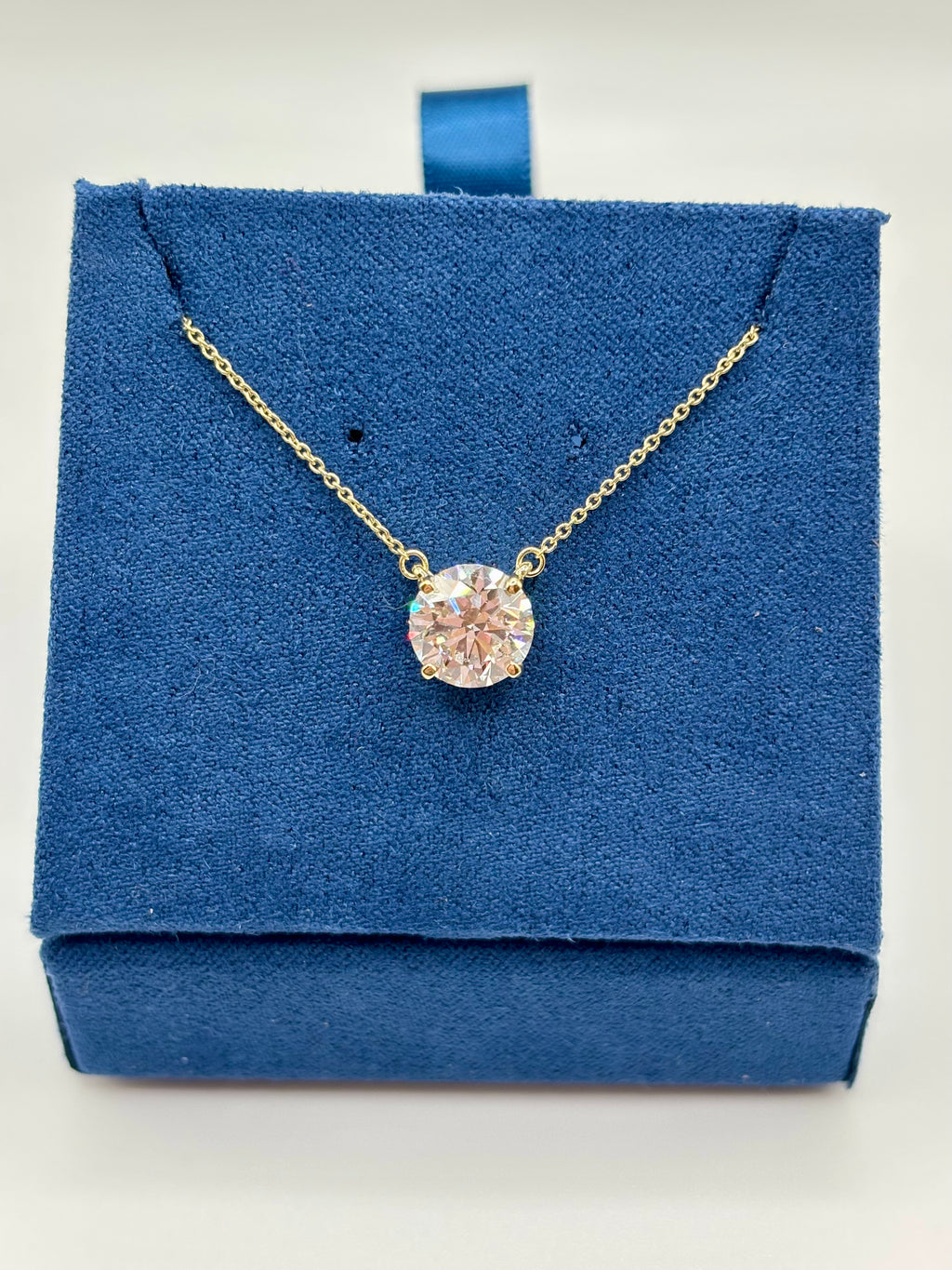 Lab diamond solitaire necklace in 14K yellow gold on blue box, full view