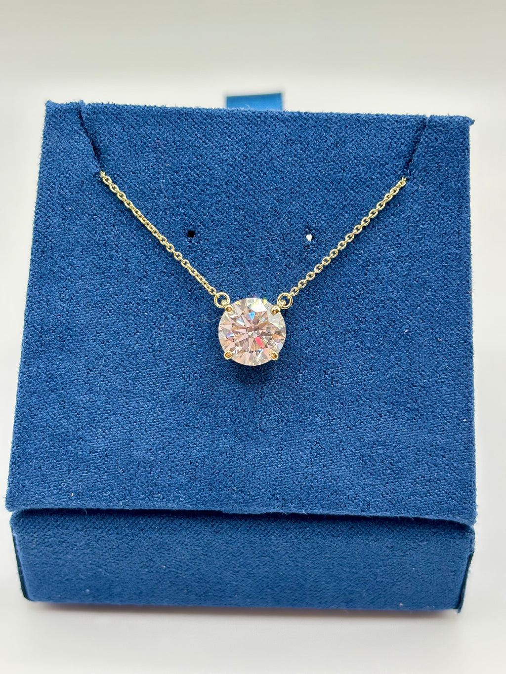 2 carat lab diamond solitaire station necklace in 14K yellow gold on blue velvet box, top view