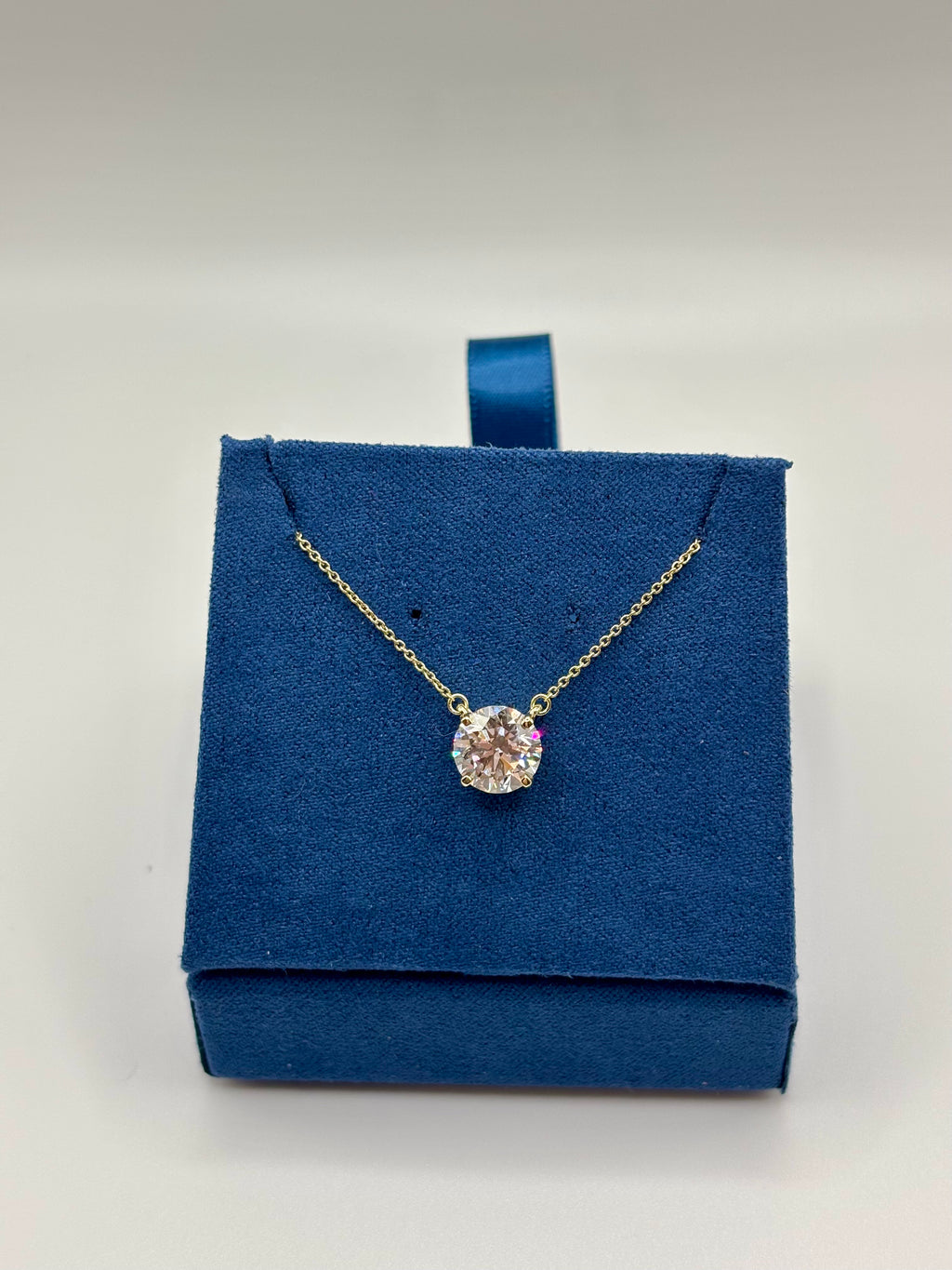 2ct lab diamond solitaire necklace on blue jewelry box, side view