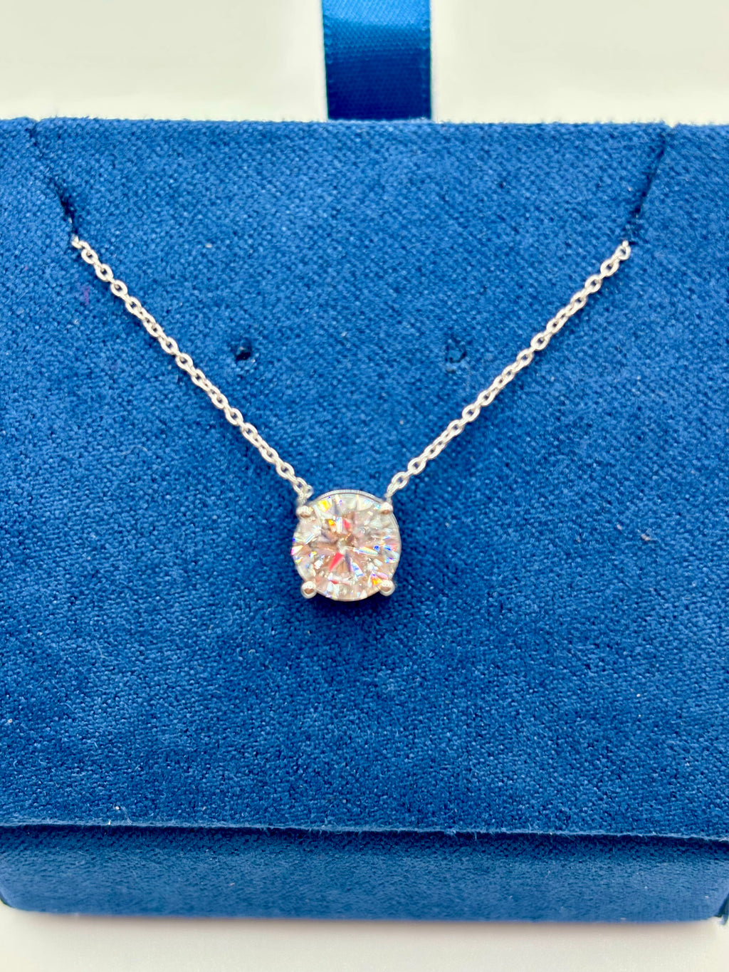 Round brilliant 1.5 carat lab diamond solitaire necklace in white gold, close-up on blue box