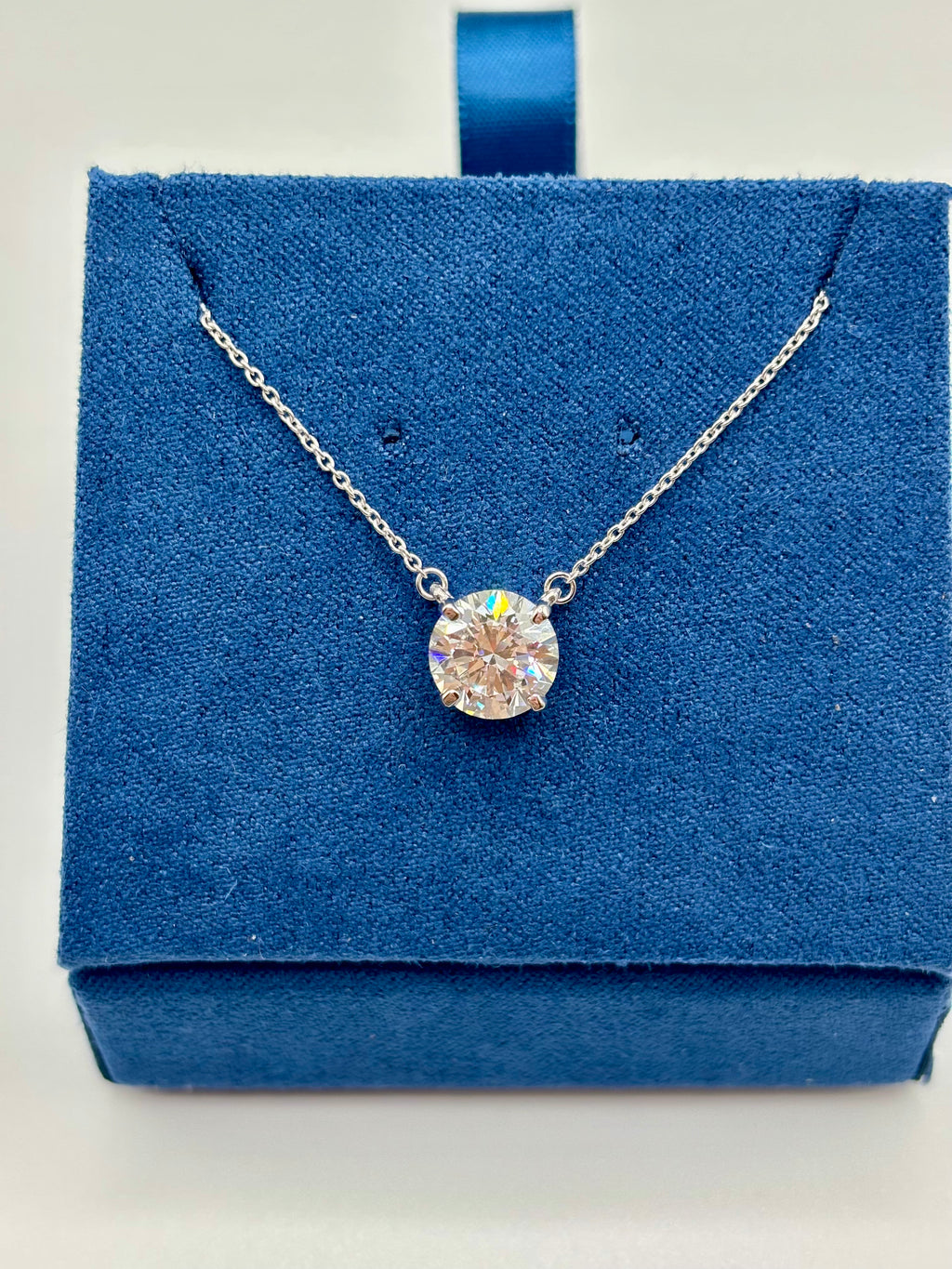 2ct lab diamond pendant on 14K white gold cable chain, front view on blue box