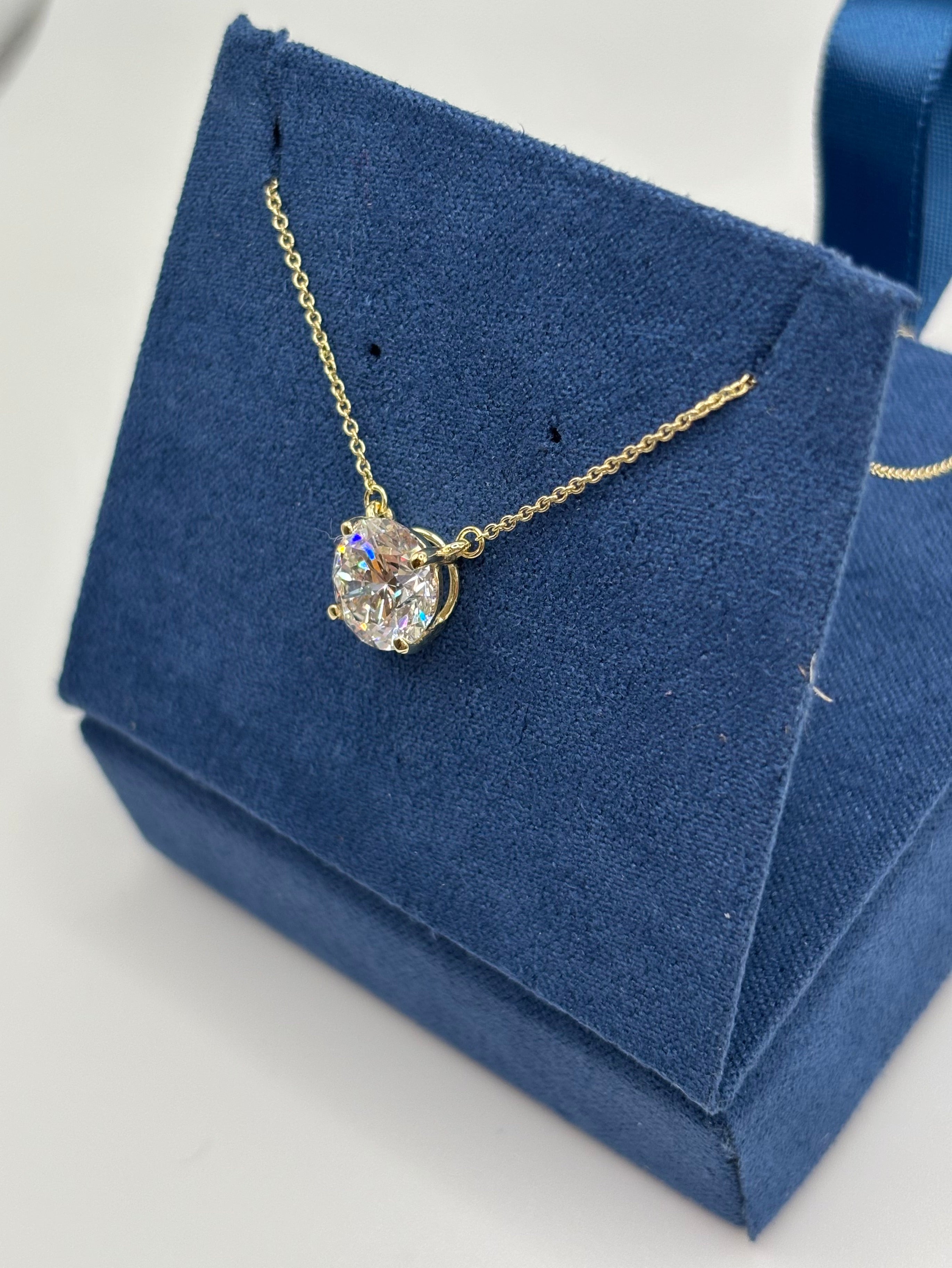 Round brilliant 2 carat lab diamond pendant on 14K yellow gold chain, angled close-up