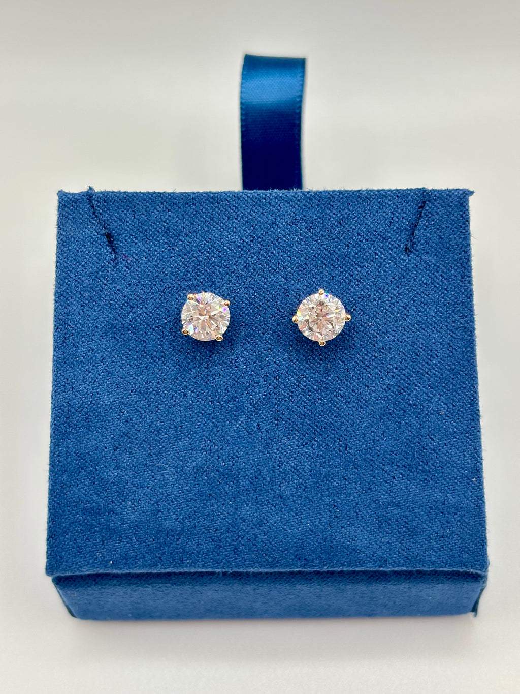 Round brilliant lab diamond studs in 14K yellow gold four-prong setting on blue box