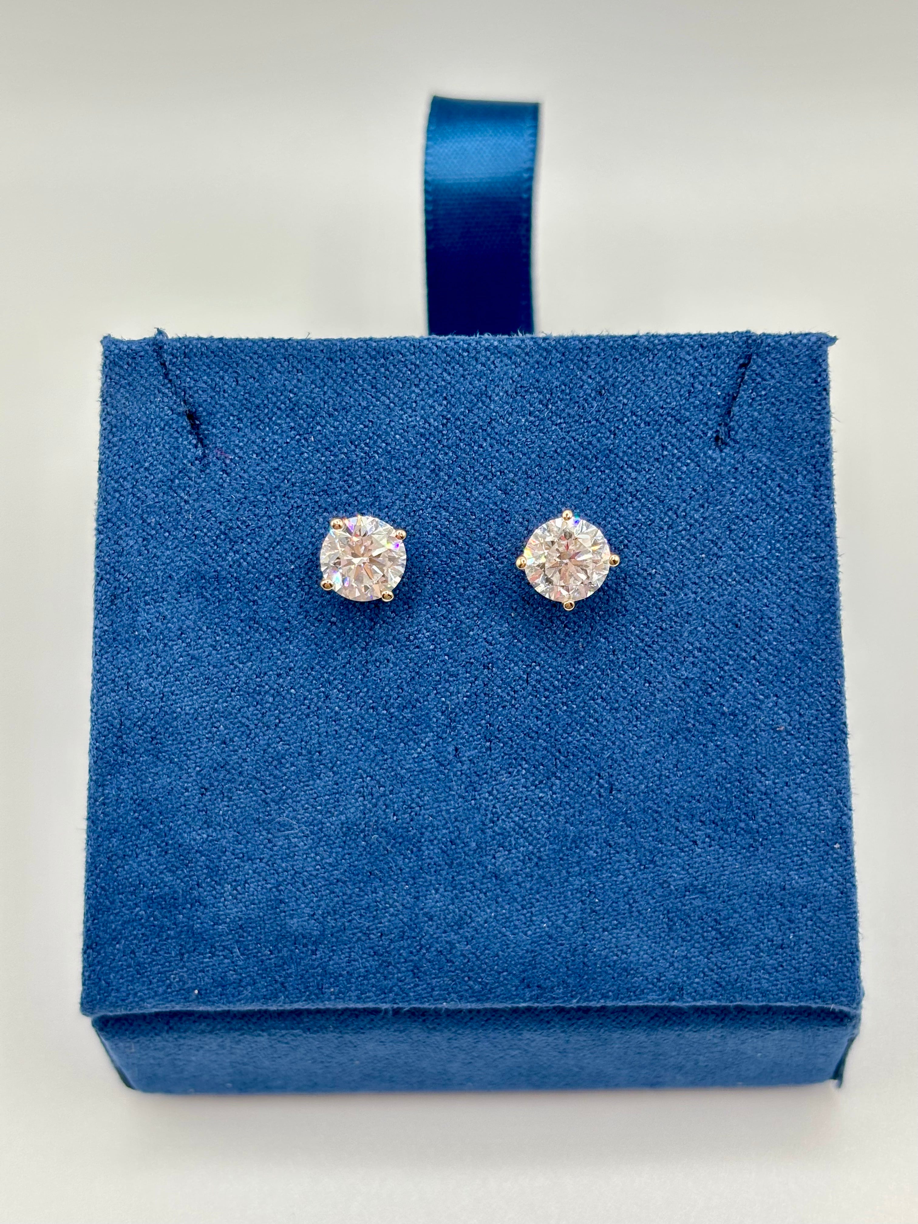 Round brilliant lab diamond studs in 14K yellow gold four-prong setting on blue box