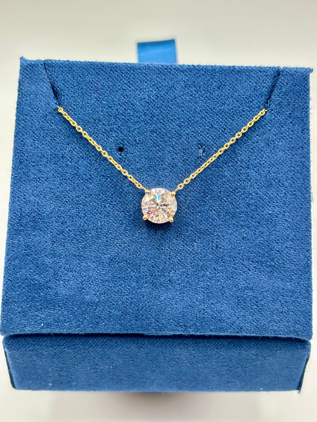 1 carat lab diamond solitaire station necklace in 14K yellow gold on blue velvet box