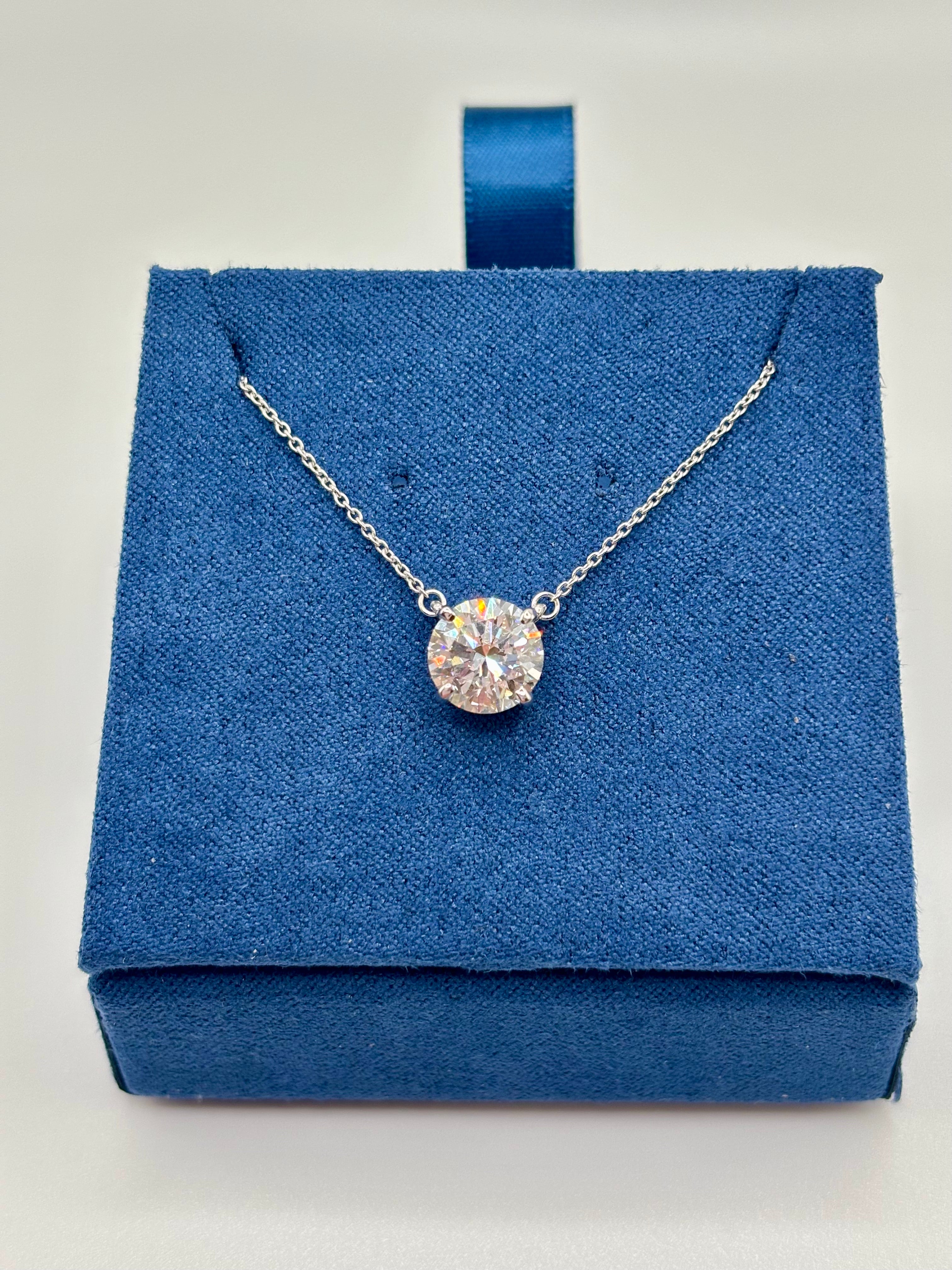 Round brilliant 2 carat lab diamond solitaire necklace in white gold, close-up on blue box
