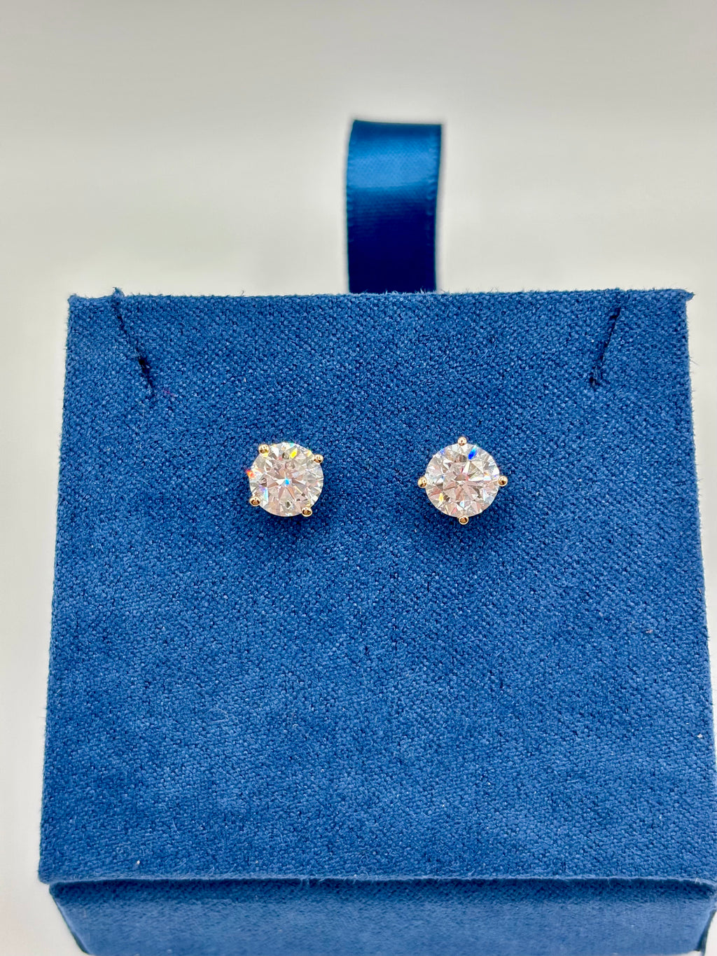 2 CTW lab diamond solitaire stud earrings in 14K yellow gold on blue velvet box, top view